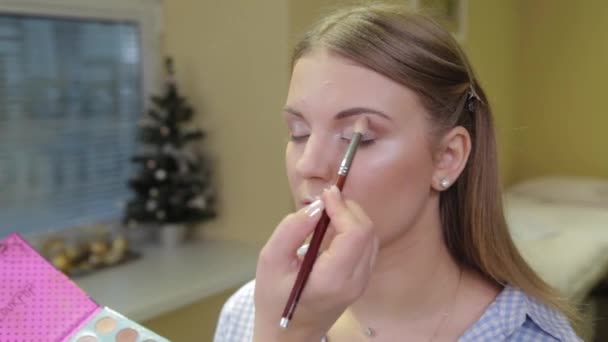 Professional make-up artist with a brush applies eye shadow to a client in a beauty salon. — Stock Video