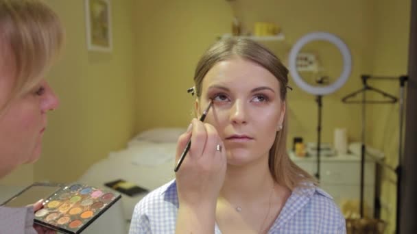 Un maquilleur professionnel au pinceau applique une ombre à paupières à un client dans un salon de beauté . — Video