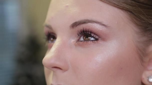 Professionell makeup artist målar ögonfransar till en kund. — Stockvideo