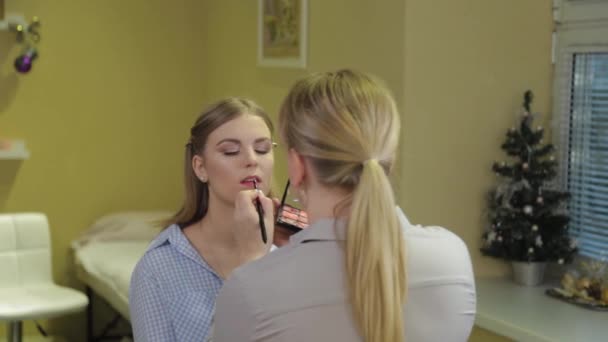 Professionele make-up artiest poetsen lippenstift op de lippen van de klant. — Stockvideo