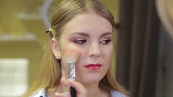 Profesionální make-up umělec kartáčování prášek na tváři klienta. — Stock video