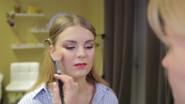 Profesionální make-up umělec kartáčování prášek na tváři klienta. — Stock video