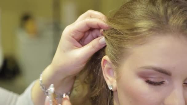Profesjonalny fryzjer kładzie spinkę do włosów na głowie dziewczyny. — Wideo stockowe