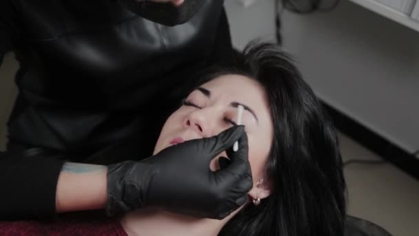 Professionelle Permanent Make-up Artist Anwendung Narkosemittel auf die Augenbrauen des Kunden. — Stockvideo