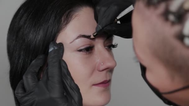 Profesjonalny makijażysta permanentnie maluje brwi dla klienta. — Wideo stockowe