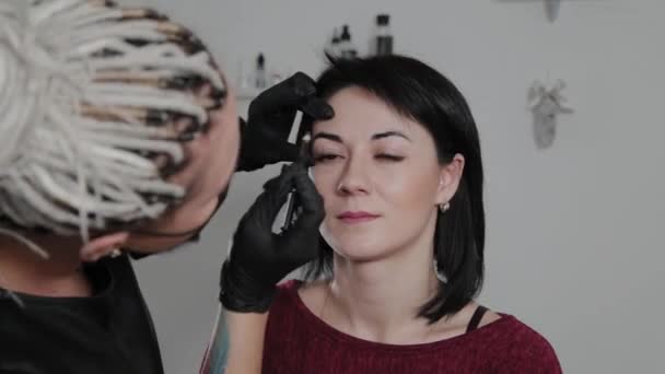 Επαγγελματική μόνιμη make-up καλλιτέχνης κάνει φρύδια σήμανση για έναν πελάτη. — Αρχείο Βίντεο