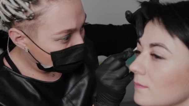 Profesjonalny makijażysta permanentnie maluje brwi dla klienta. — Wideo stockowe