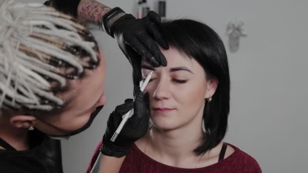 Professional permanent make-up artist does eyebrow marking for a client. — Stock Video