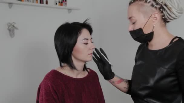 Un maquilleur professionnel permanent effectue le marquage des sourcils pour un client . — Video