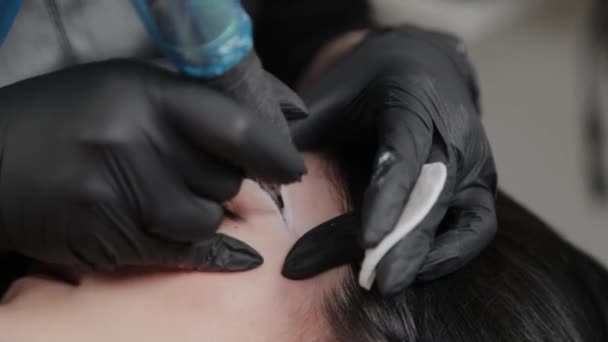 A professional permanent makeup artist does permanent eyebrow makeup with a tattoo machine. — Stockvideo