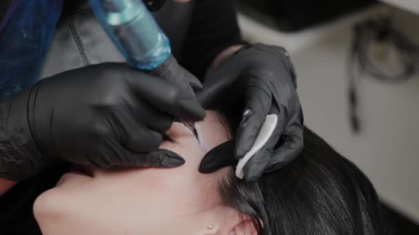 A professional permanent makeup artist does permanent eyebrow makeup with a tattoo machine. — Stok video