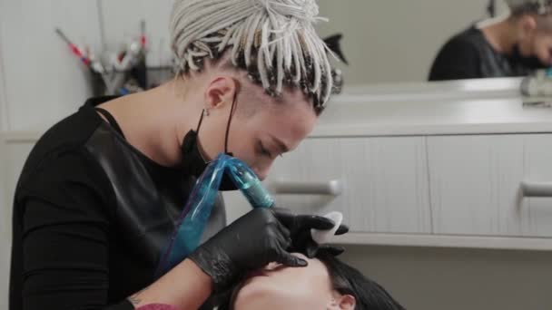 Un artista de maquillaje permanente profesional hace maquillaje de cejas permanente con una máquina de tatuaje . — Vídeos de Stock