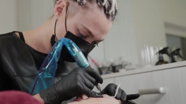 A professional permanent makeup artist does permanent eyebrow makeup with a tattoo machine. — Stok video