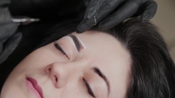 A professional permanent makeup artist does permanent eyebrow makeup with a tattoo machine. — Stockvideo