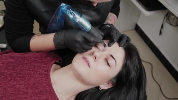 A professional permanent makeup artist does permanent eyebrow makeup with a tattoo machine. — 비디오