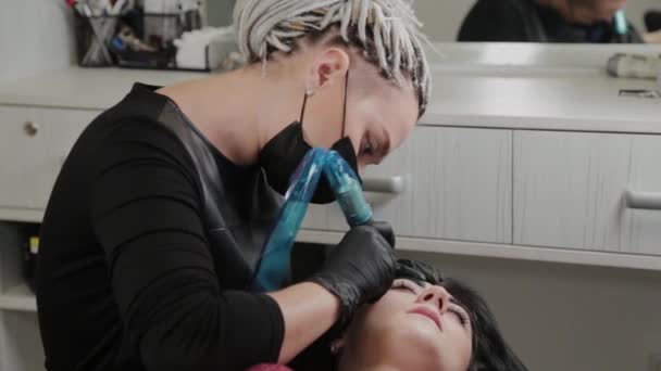 A professional permanent makeup artist does permanent eyebrow makeup with a tattoo machine. — Stock Video