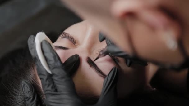 Un truccatore permanente professionale fa il trucco permanente del sopracciglio con una macchina del tatuaggio . — Video Stock