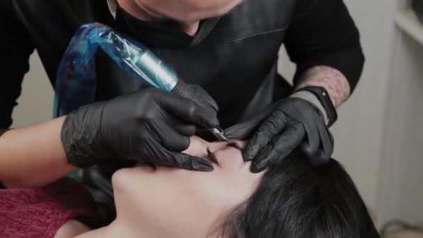 Un artista de maquillaje permanente profesional hace maquillaje de cejas permanente con una máquina de tatuaje . — Vídeos de Stock