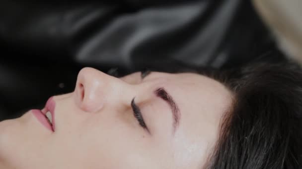 A professional permanent makeup artist does permanent eyebrow makeup with a tattoo machine. — Stok video