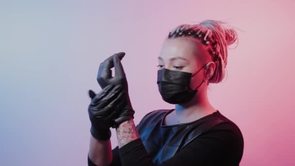 Young girl with dreadlocks puts on rubber gloves. — Stock Video