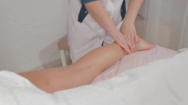 Vrouw massage therapeut doet massage op de benen van een jong meisje. — Stockvideo