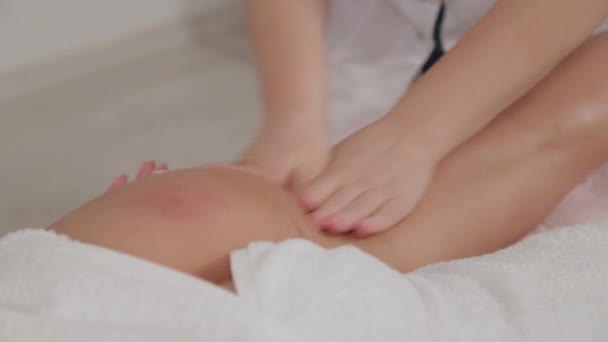 Mujer terapeuta de masaje hace masaje en las piernas de una niña . — Vídeos de Stock