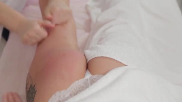 Masseurin massiert über die gesamte Länge der Beine eines jungen Mädchens. — Stockvideo