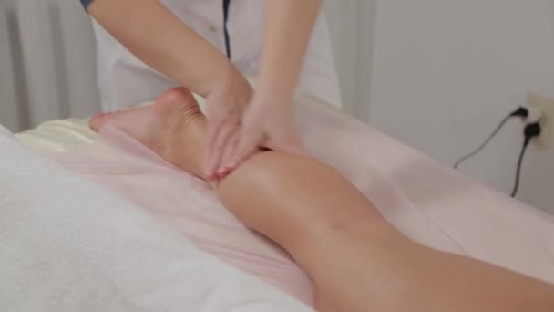 Kvinna massage terapeut gör massage på vadmusklerna hos en ung flicka. — Stockvideo