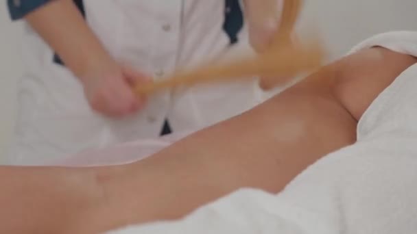 Γυναίκα θεραπεύτρια μασάζ κάνει μασάζ με μπαμπού μπαστούνια σε ένα νεαρό κορίτσι. — Αρχείο Βίντεο