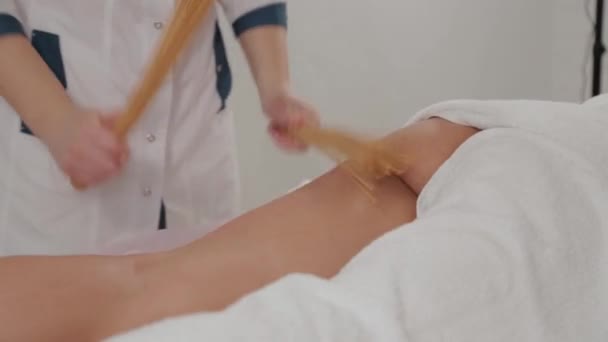 Massagetherapeutin massiert ein junges Mädchen mit Bambusstäben. — Stockvideo