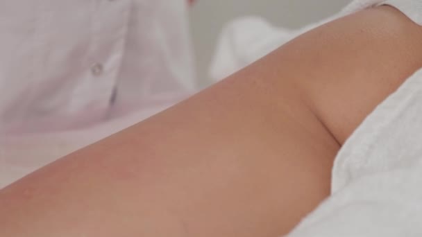 Massaggiatore donna versa olio sulla gamba di una giovane ragazza . — Video Stock