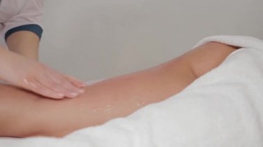 Woman massage therapist makes honey massage to a young girl in a massage parlor.