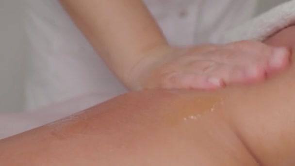 Woman massage therapist makes honey massage to a young girl in a massage parlor. — Stockvideo
