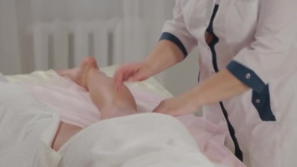 Woman massage therapist does massage on the legs of a young girl in a massage parlor. — ストック動画