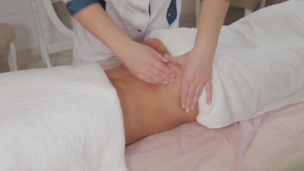 Женщина-массажист делает массаж по бокам молодой девушки в массажном салоне . — стоковое видео