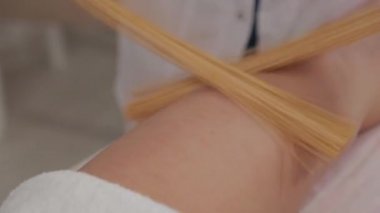Woman massage therapist doing massage with bamboo sticks to a young girl.