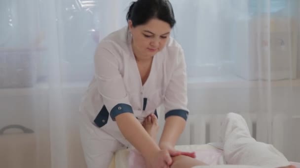 Massothérapeute féminine faisant du massage sur toute la longueur des jambes d'une jeune fille . — Video