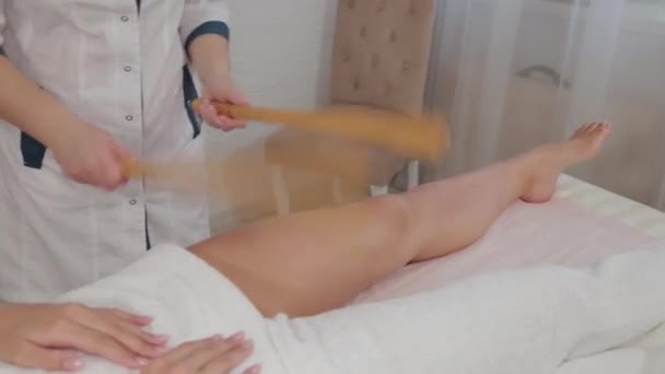 Woman massage therapist doing massage with bamboo sticks to a young girl. — Stock Video
