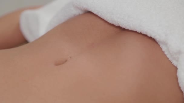 Vrouw massage therapeut schenkt massage olie op de maag van een jong meisje. — Stockvideo