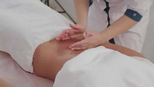Vrouw massage therapeut doet massage op de maag van een jong meisje. — Stockvideo
