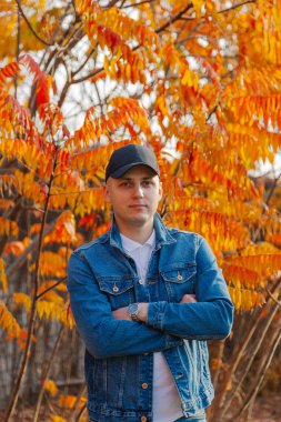 Sonbaharda sarı yapraklı arka planda bir adam.