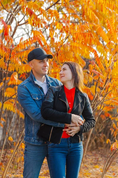 Pasangan bahagia jatuh cinta pada latar belakang daun kuning di musim gugur . — Stok Foto