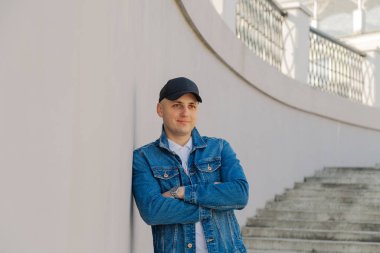 Beton bir merdivende beyzbol şapkalı yakışıklı bir adam..