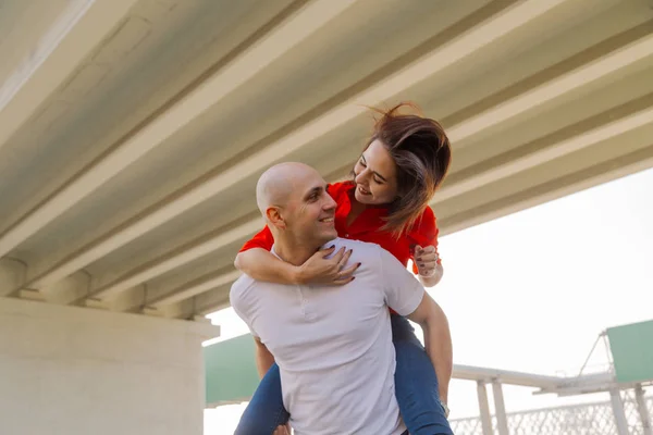 Menina feliz na parte de trás de um homem na ponte. Os amantes se divertem . — Fotografia de Stock