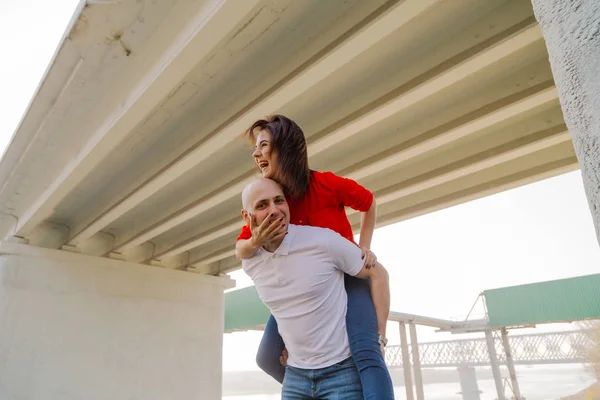 Lycklig flicka på baksidan av en man vid bron. Lovers ha kul. — Stockfoto