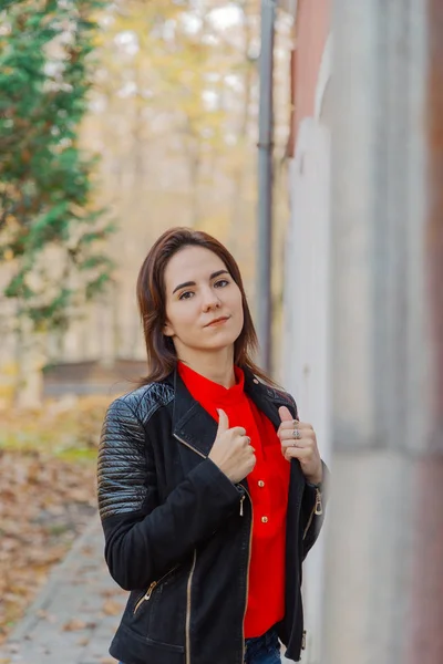 Beautiful portrait of a girl in a park near the wall. — Stock Photo, Image