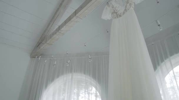 Beautiful modern wedding dress hanging in the house. — Stock Video