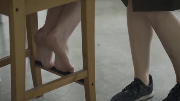 Girl on a chair does makeup by a makeup artist. The legs of two girls in the frame. — Stok video