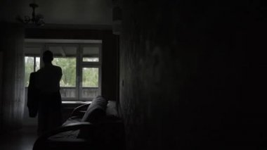 Yetişkin erkek işadamı pencereye bir ceket koyar..