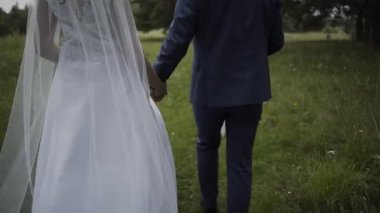 Mutlu yeni evliler el ele tutuşup yürür.